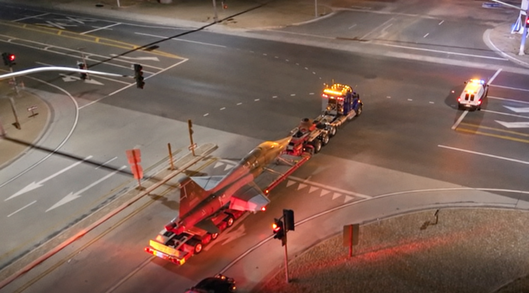 The aircraft and its transport truck crossing a lit intersection at night